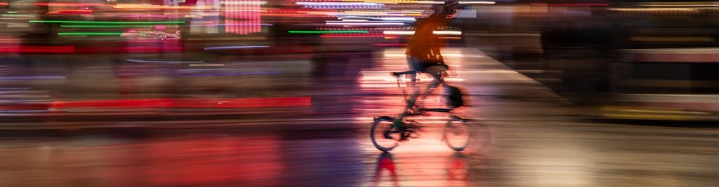 Cyclist riding a bicycle through a city in the evening